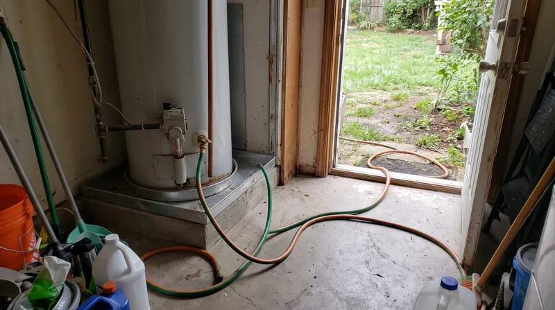 Garden hose connected to a water heater drain valve and run out the back door to flush the tank